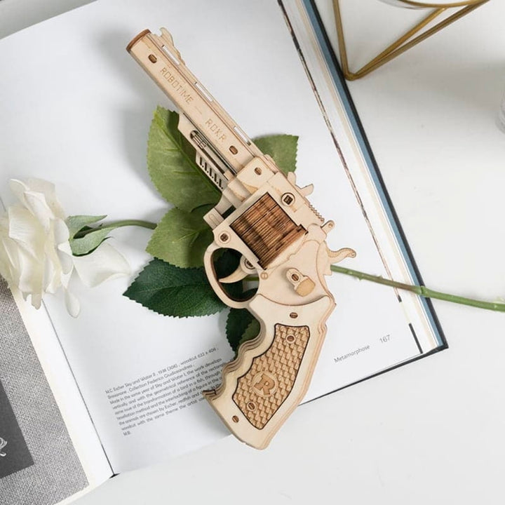 Wooden revolver model on an open book with a white rose