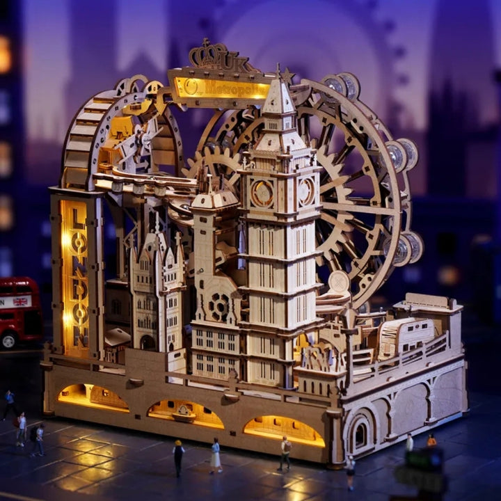 Wooden model of a clock tower with mechanical gears and lights, set against a blurred cityscape background.