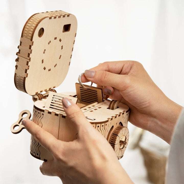Wooden mechanical model being assembled by a person's hands on a light background