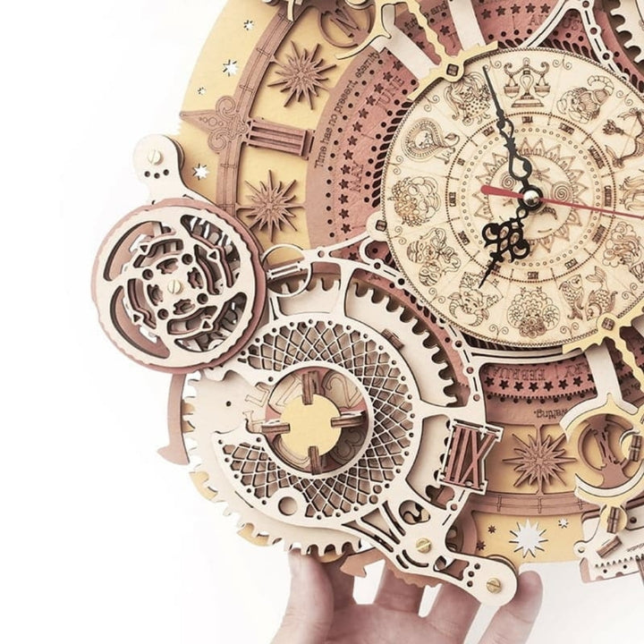 Wooden mechanical clock model held by a hand on a white background