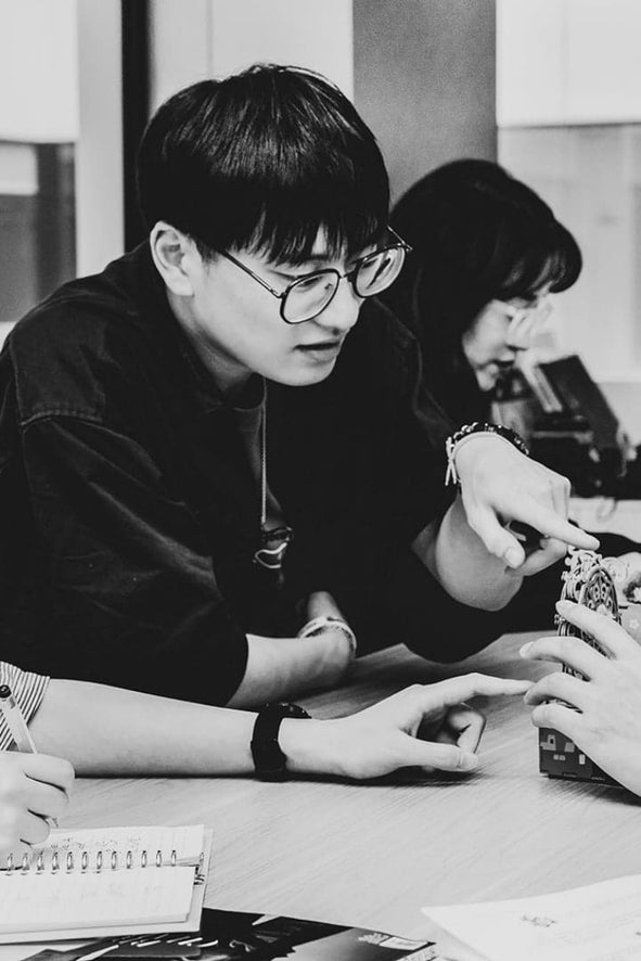 Two people sitting at a table with one person holding a small object