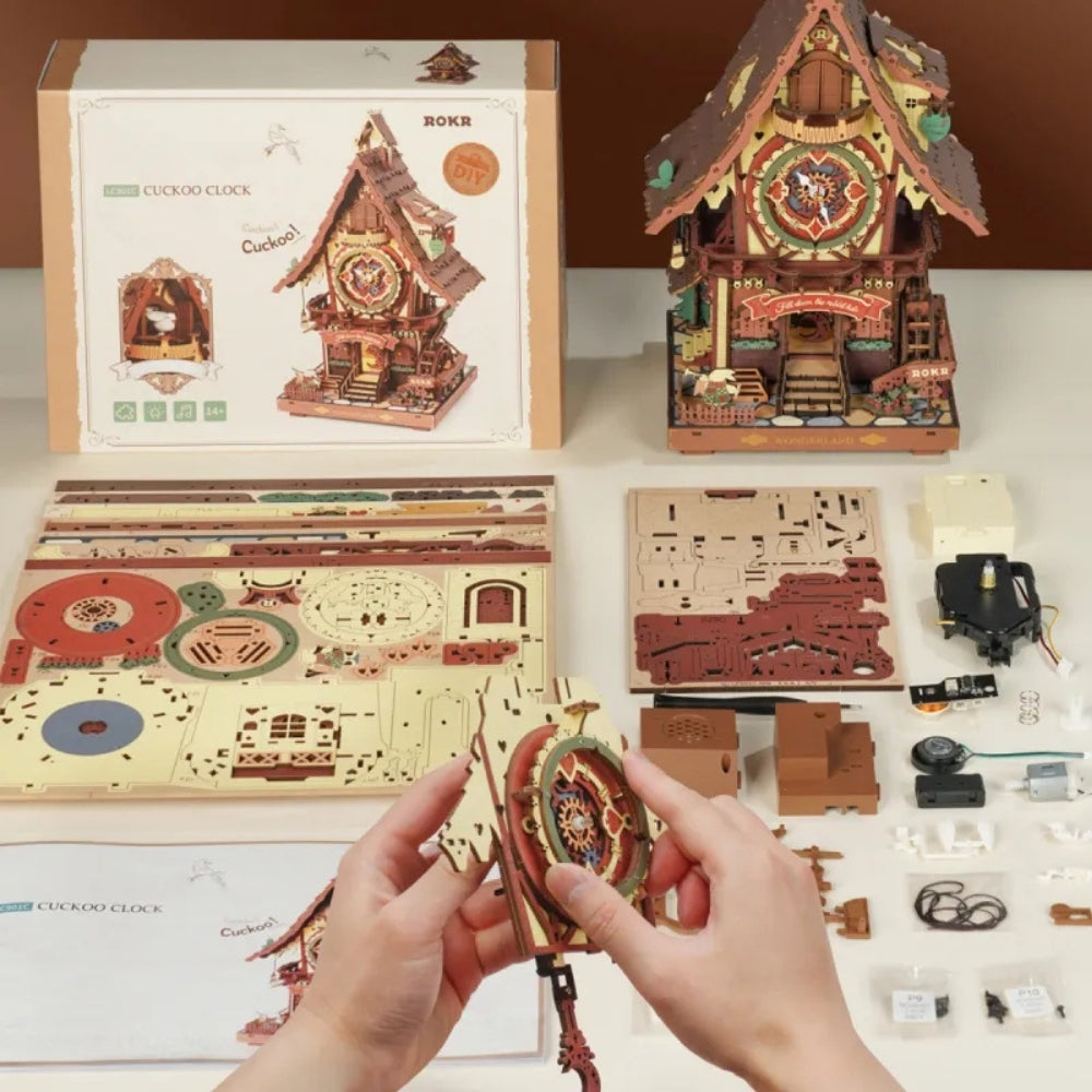 Wooden cuckoo clock model kit with packaging and components on a table