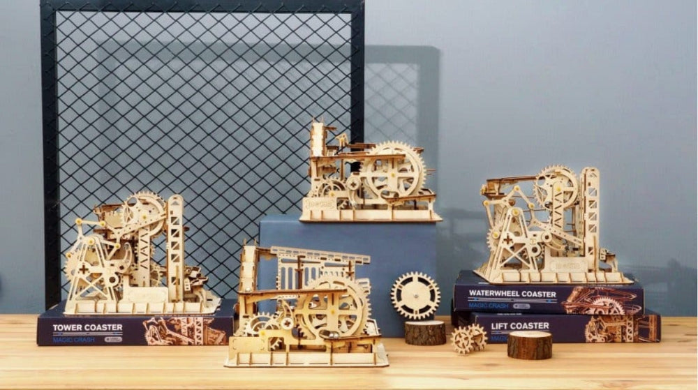 Mechanical model kits on a wooden surface with a grid patterned screen in the background.